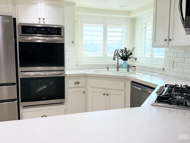 kitchen featuring tasteful backsplash, white cabinetry, sink, and appliances with stainless steel finishes