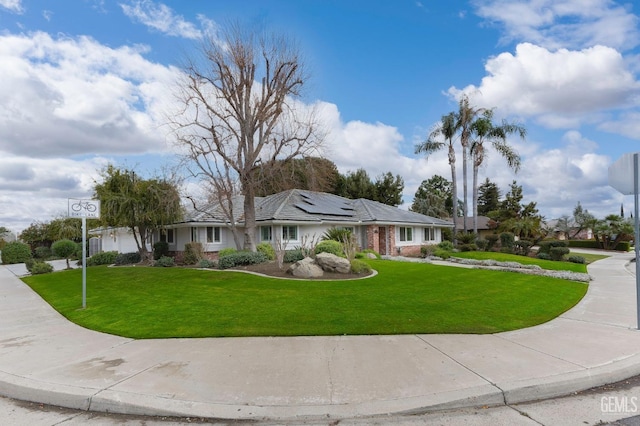 single story home with roof mounted solar panels and a front lawn