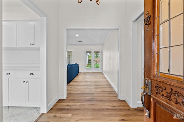 entrance foyer with light wood-style flooring, baseboards, and crown molding