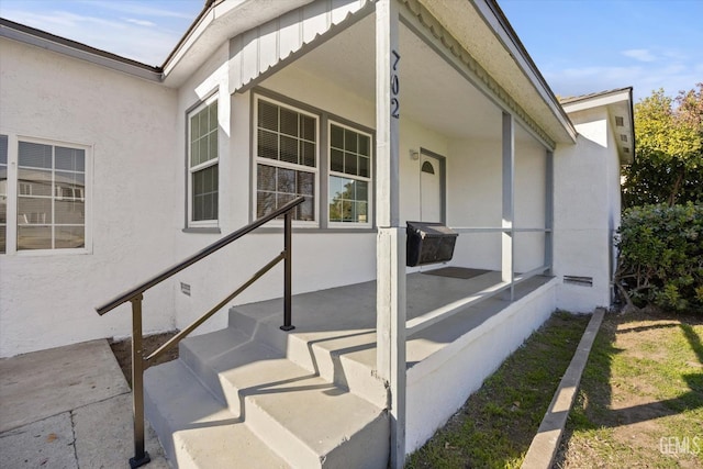 view of exterior entry featuring covered porch