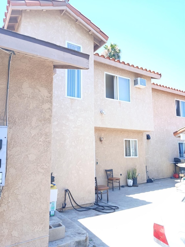 rear view of property with an AC wall unit and a patio area