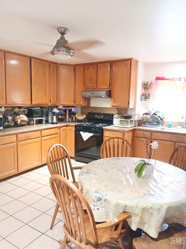 kitchen featuring ceiling fan, sink, black gas range oven, backsplash, and light tile patterned floors