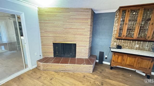 bar with crown molding, a stone fireplace, and dark wood-type flooring