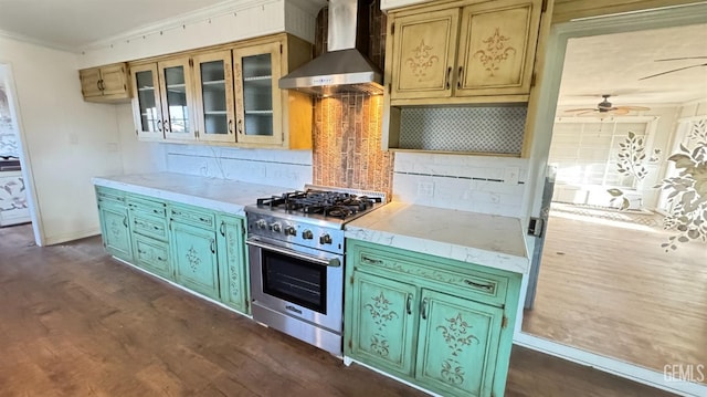 kitchen with stainless steel stove, tasteful backsplash, ornamental molding, dark hardwood / wood-style flooring, and wall chimney exhaust hood