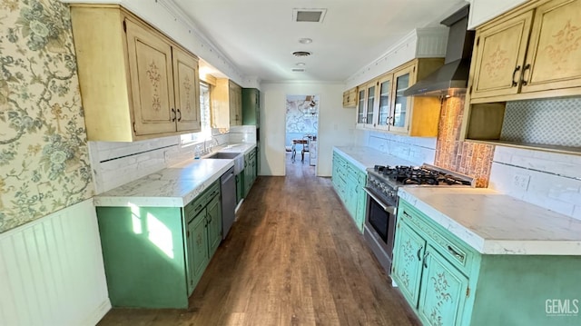 kitchen with appliances with stainless steel finishes, dark hardwood / wood-style flooring, decorative backsplash, crown molding, and wall chimney range hood