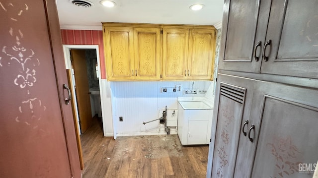 washroom featuring wood walls, cabinets, hookup for a washing machine, crown molding, and light hardwood / wood-style flooring