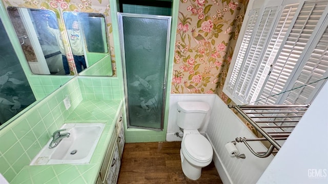 bathroom featuring wood-type flooring, toilet, a shower with shower door, and sink