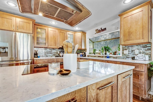 kitchen featuring decorative backsplash, light brown cabinets, light stone countertops, and stainless steel refrigerator with ice dispenser