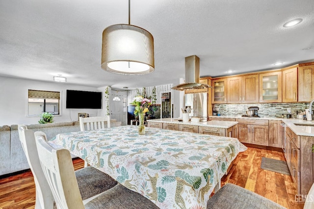 dining space with a textured ceiling, light hardwood / wood-style floors, and sink