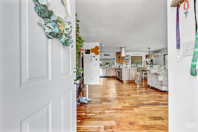 foyer with a wall unit AC, a textured ceiling, and hardwood / wood-style flooring