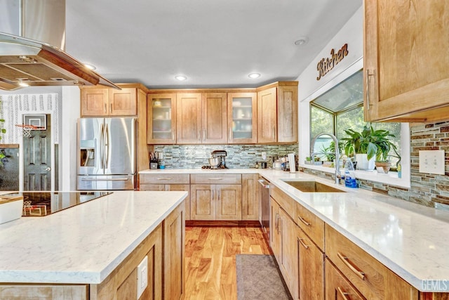 kitchen featuring backsplash, sink, light stone countertops, island range hood, and stainless steel appliances