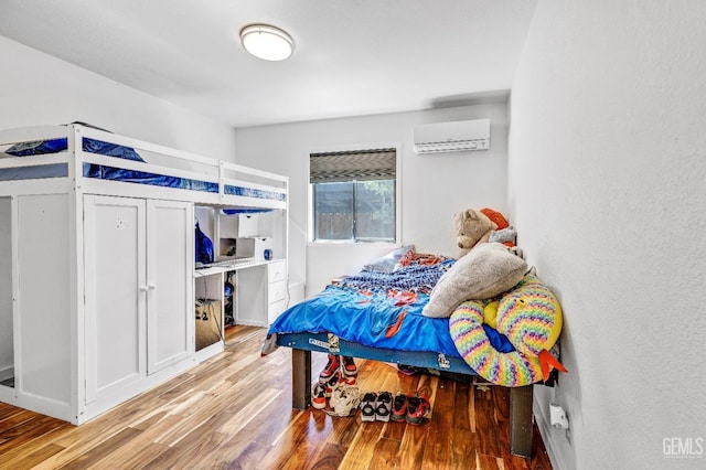 bedroom with light wood-type flooring and a wall mounted AC