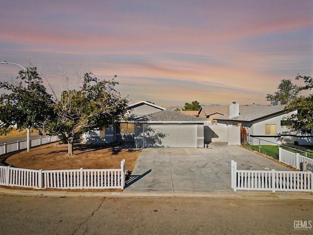 ranch-style home featuring concrete driveway, an attached garage, and a fenced front yard