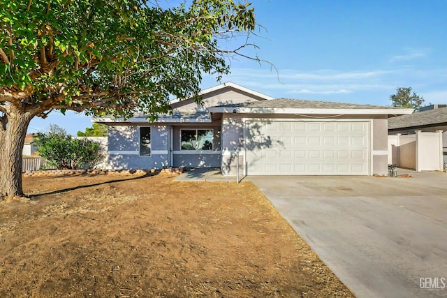 ranch-style home with driveway, stucco siding, fence, and an attached garage