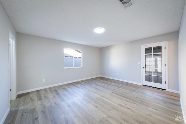 unfurnished room featuring light wood finished floors, baseboards, and visible vents