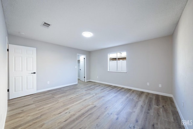 empty room featuring light wood-style floors, visible vents, and baseboards