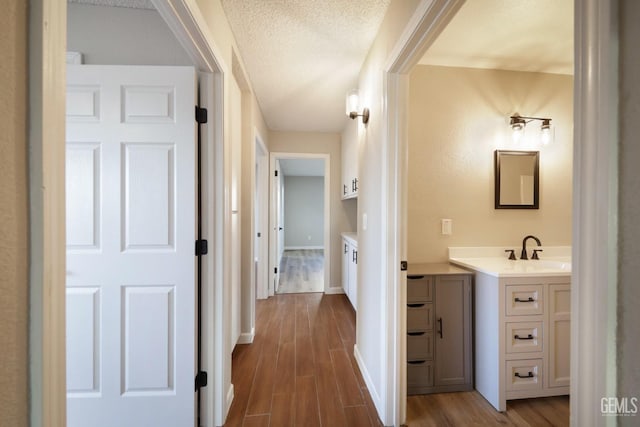 bathroom featuring baseboards, vanity, wood finished floors, and a textured ceiling