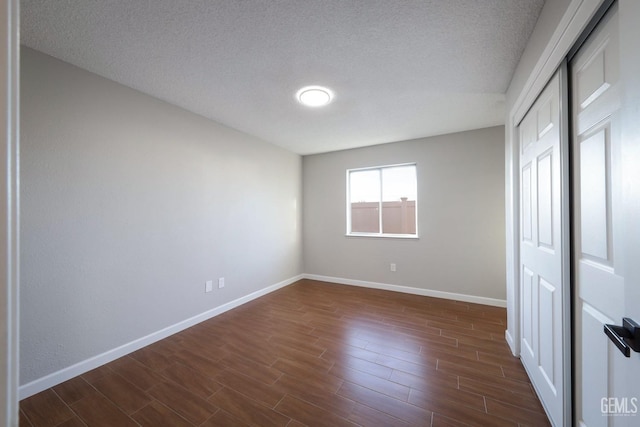 unfurnished bedroom featuring dark wood-type flooring, a closet, and baseboards