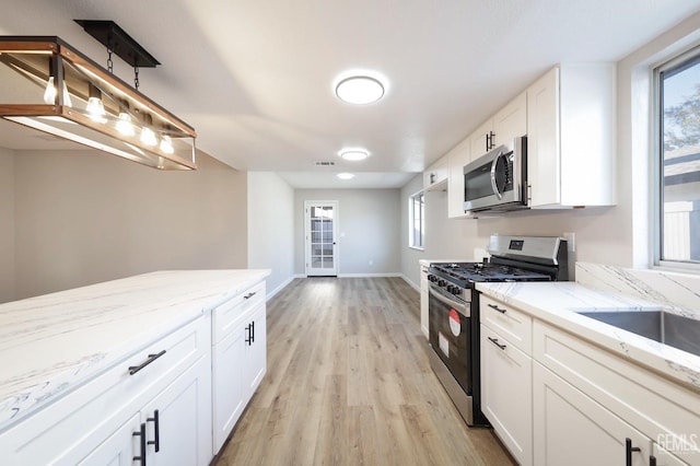 kitchen featuring white cabinets, light stone countertops, light wood-style floors, visible vents, and stainless steel appliances