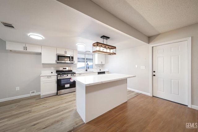 kitchen featuring visible vents, light wood-style flooring, white cabinetry, and stainless steel appliances