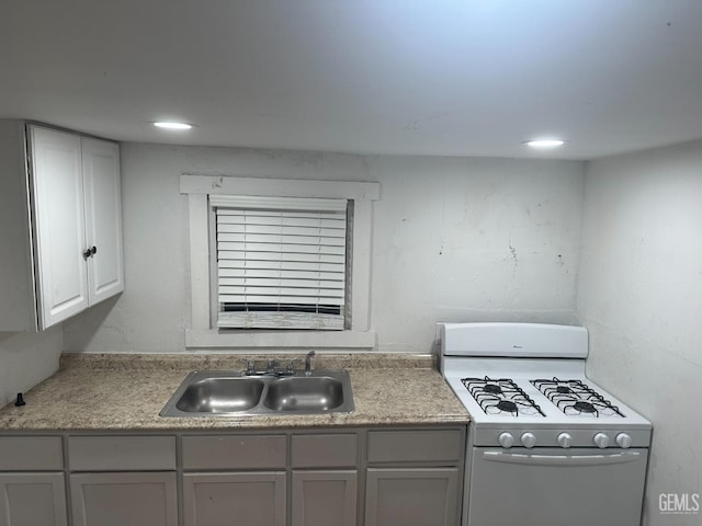 kitchen featuring light countertops, gas range gas stove, a sink, and recessed lighting