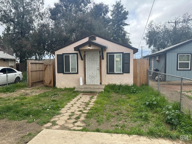 bungalow featuring fence and stucco siding