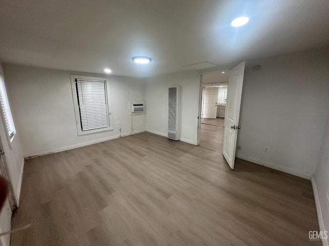 unfurnished room featuring light wood-style flooring, baseboards, and a wall mounted AC