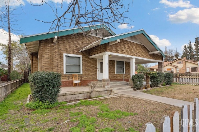 view of front of property with a front yard, fence, a carport, and brick siding