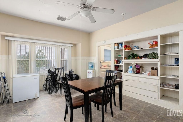 tiled dining area featuring a ceiling fan, wainscoting, and visible vents