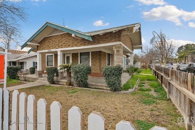 view of home's exterior with fence private yard, a porch, and brick siding