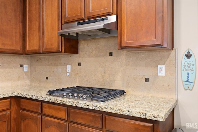 9221 Via Lugano, Bakersfield, CA 93312 - kitchen with under cabinet range hood, stainless steel gas stovetop, decorative backsplash, and brown cabinetry
