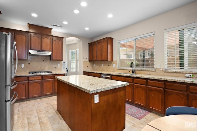 9221 Via Lugano, Bakersfield, CA 93312 - kitchen with stainless steel appliances, under cabinet range hood, a sink, arched walkways, and a kitchen island