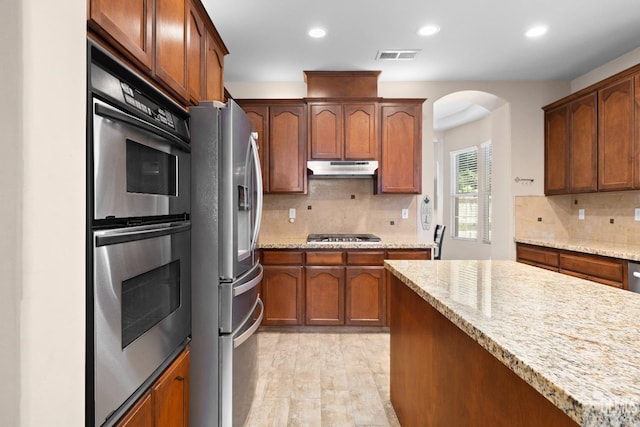 9221 Via Lugano, Bakersfield, CA 93312 - kitchen featuring appliances with stainless steel finishes, arched walkways, recessed lighting, under cabinet range hood, and backsplash