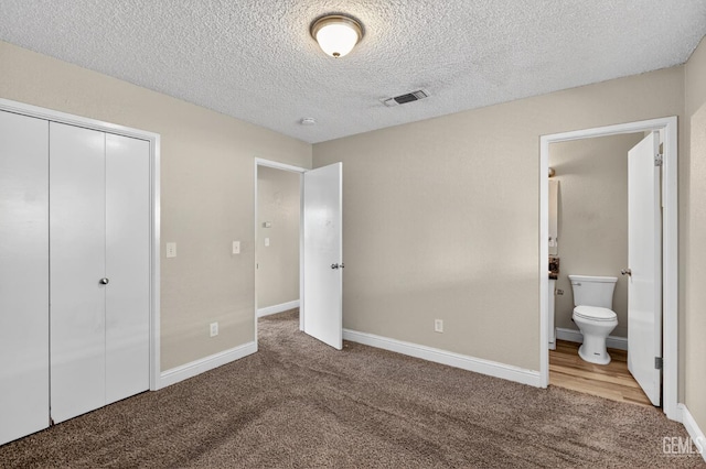 1929 Belmont St, Delano, CA 93215 - unfurnished bedroom featuring carpet, a textured ceiling, baseboards, connected bathroom, and a closet