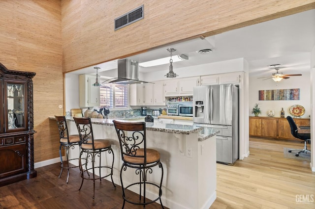 601 Vista Verde Way, Bakersfield, CA 93309 - kitchen with stainless steel appliances, island exhaust hood, a peninsula, white cabinets, and light stone counters