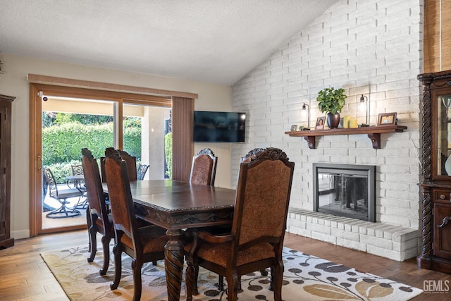 601 Vista Verde Way, Bakersfield, CA 93309 - dining room with vaulted ceiling, wood finished floors, a textured ceiling, and a brick fireplace