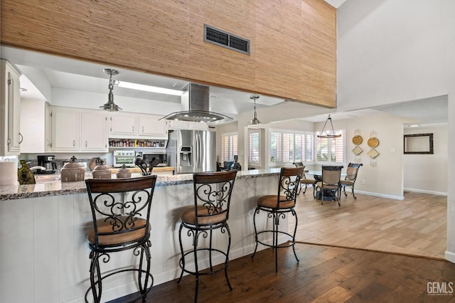 601 Vista Verde Way, Bakersfield, CA 93309 - kitchen featuring appliances with stainless steel finishes, island exhaust hood, a peninsula, a towering ceiling, and wood finished floors