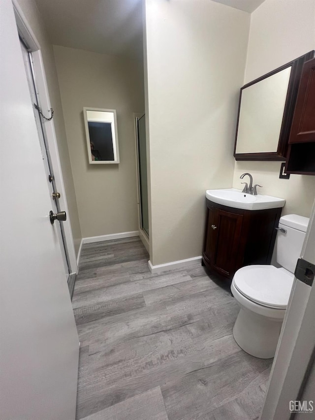 bathroom featuring vanity, hardwood / wood-style flooring, toilet, and walk in shower