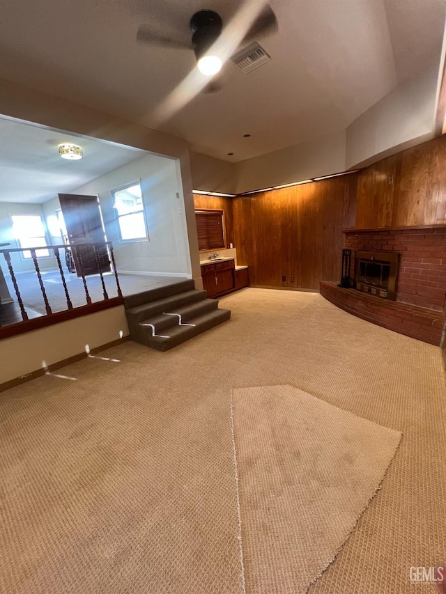 unfurnished living room featuring light carpet, a brick fireplace, and wooden walls