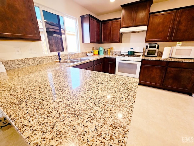 kitchen with sink, light stone counters, and white appliances