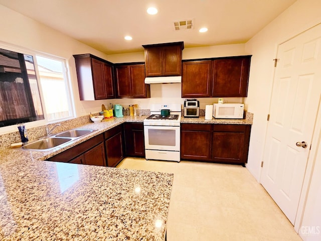 kitchen with light stone counters, sink, and white appliances