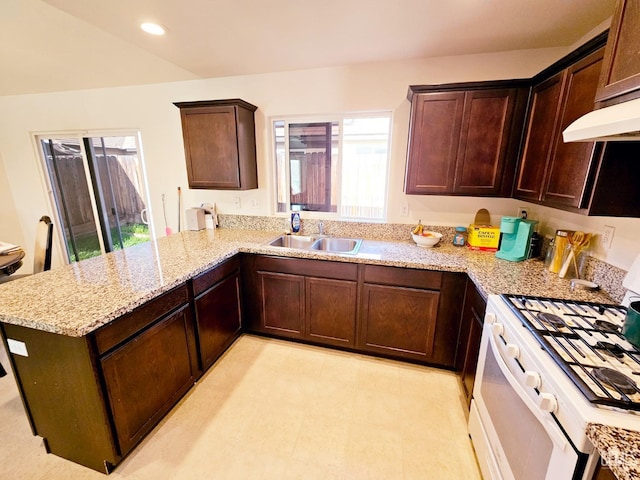 kitchen with light stone countertops, gas range gas stove, kitchen peninsula, and sink