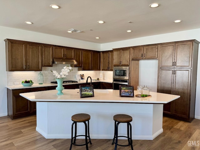 kitchen with stainless steel appliances, light countertops, visible vents, and under cabinet range hood