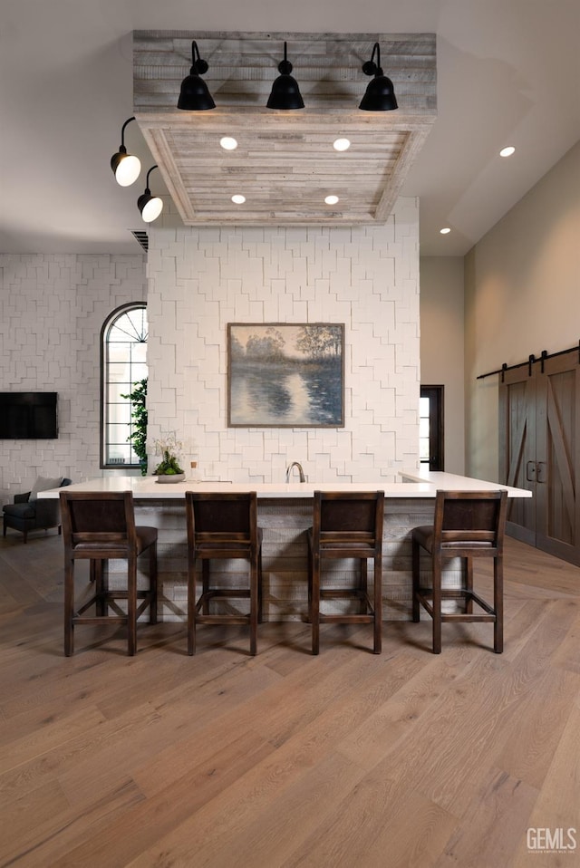 bar with light wood-type flooring, a barn door, visible vents, and recessed lighting