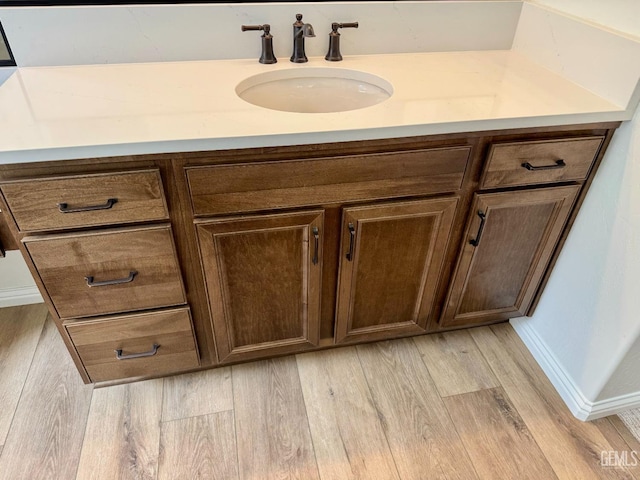 bathroom with a sink, baseboards, and wood finished floors