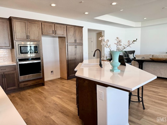 kitchen with light wood-style flooring, appliances with stainless steel finishes, a breakfast bar, and a sink