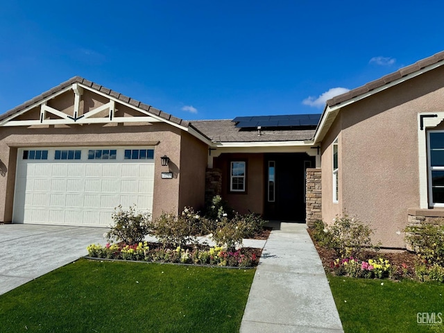 view of front of home with stucco siding, roof mounted solar panels, a garage, stone siding, and a front lawn