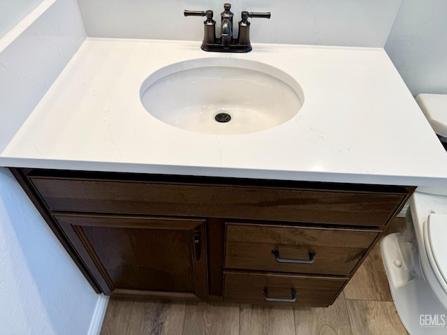 half bathroom featuring vanity, toilet, and wood finished floors