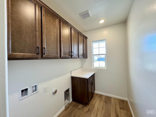 laundry area featuring washer hookup, cabinet space, visible vents, light wood-style floors, and baseboards