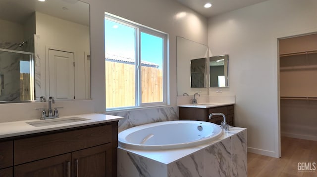 16903 Mairs Dr, Bakersfield, CA 93314 - bathroom featuring a marble finish shower, a garden tub, two vanities, wood finished floors, and a walk in closet